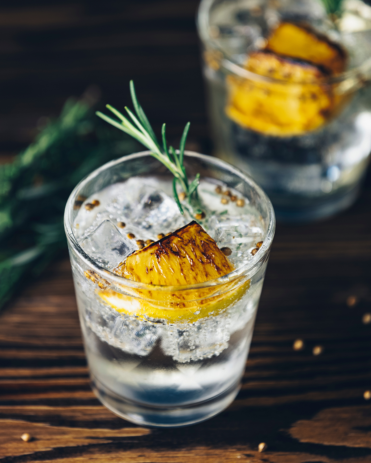 Zwei Gläser mit Gin Tonic und einer Zitronenscheibe und Rosmarinzweig.